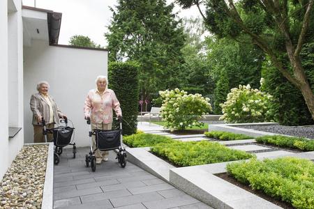 Zwei ältere Frauen mit Rollatoren verlassen die Praxis.