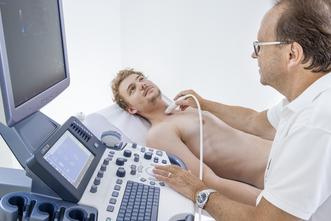 Arzt untersucht den Hals eines Patienten mit dem Ultraschallgerät.