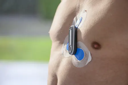 Die nackte Brust eines Mannes mit aufgeklebtem, kabellosem Langzeit-EKG.