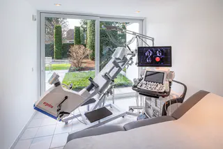 Arzt schaut auf Ultraschallmonitor. Ein Patient auf einem Ergometer.